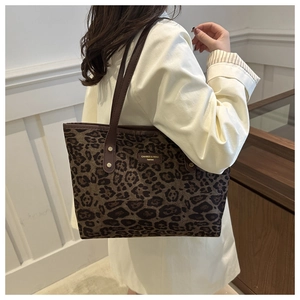 Detail of leopard print tote bag featuring brown leather handles and golden rivets