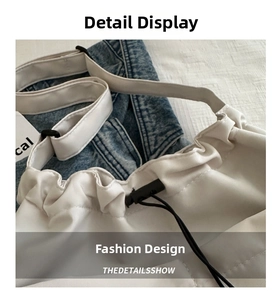 Detail of white nylon shoulder bag with black drawstring closure and wide adjustable strap