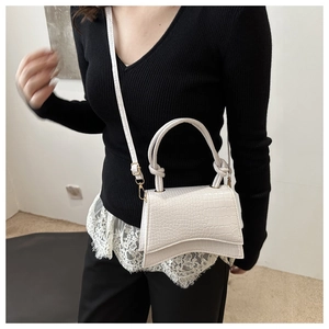Macro shot of white crocodile embossed hourglass handbag with curved base and top handle