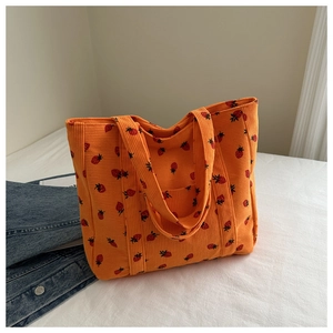Detailed close-up of orange corduroy tote bag with strawberry prints and soft texture