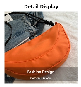 Close-up of orange nylon crescent bag featuring black braided rope strap and metal ring