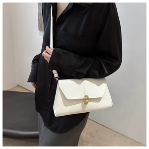 Detail of white leather shoulder bag featuring a minimalist gold circular metal clasp