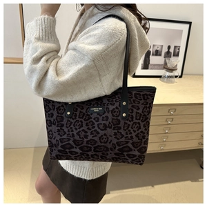 Leopard print canvas tote bag featuring slender handles and gold metal logo plaque detail
