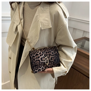 Leopard print crossbody bag with gold chain strap shown on a beige trench coat
