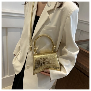 Detail of gold crocodile-patterned mini handbag with curved base and knotted handle