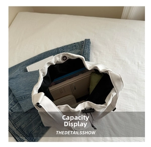 Top view of white drawstring bucket bag showing spacious interior with books and wallet