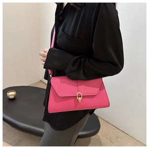Hot pink leather envelope bag with gold circular clasp shown on shoulder of a model