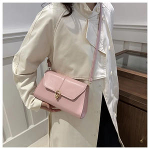Pink PU leather shoulder bag with golden interlocking metal clasp on a model in trench coat