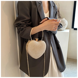 Model holding a champagne gold heart-shaped evening bag with a metallic ring handle
