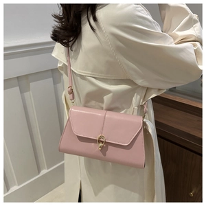 Detailed shot of pink leather underarm bag with gold metal clasp on a female model
