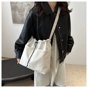 Detail of cream white drawstring bucket bag with front pockets and adjustable cord