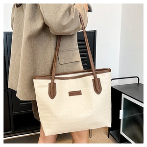 Makroaufnahme der cremeweißen Shopper-Tasche mit Reliefstruktur und braunem Lederlogo