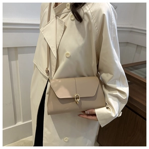 Detail of beige shoulder bag featuring elegant gold double-ring lock and textured finish