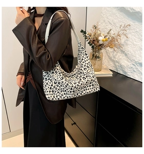 Detail of canvas shoulder bag with black leopard print pattern on white background