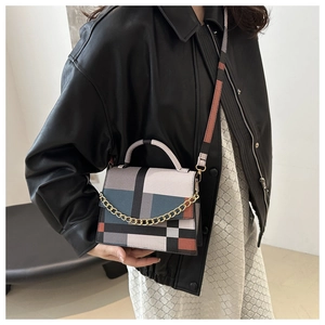 Detail of color-block flap bag with gold chain and adjustable strap on a model
