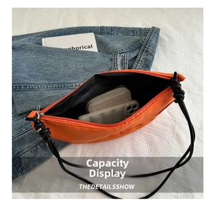Internal capacity view of the orange nylon crossbody bag holding a wallet and smartphone