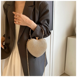 Detail of a heart-shaped gold clutch featuring sparkling sequins and a metal chain strap