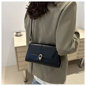 Detail of elegant black leather shoulder bag featuring a classic gold ring buckle closure