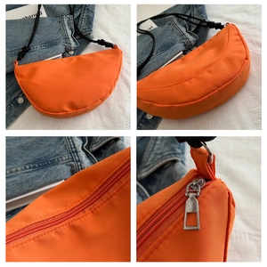 Detail view of orange crescent crossbody bag with silver zipper and nylon texture