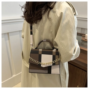Détail du sac à carreaux color-block avec chaîne dorée porté sur un trench-coat