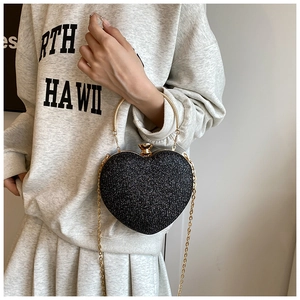 Detail of black heart-shaped glitter clutch bag with gold handle and chain strap