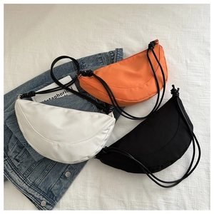 Flat lay of minimalist crescent nylon crossbody bags in white, orange, and black colors