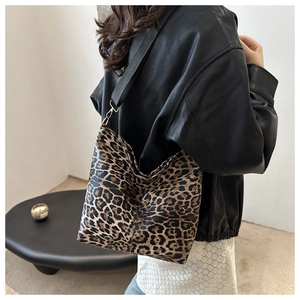 Detail of trendy leopard print hobo bag with wide black fabric strap and gold hooks