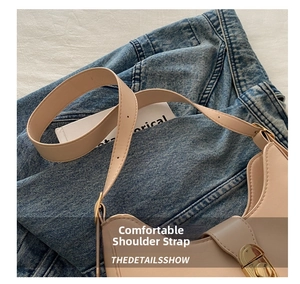 Close-up of adjustable strap and gold metal clasp on beige underarm bag with denim background