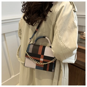 Detail of a chic plaid shoulder bag with gold chain strap on a model, back view