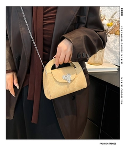 Detail of light beige leather crossbody bag with silver heart buckle and chain strap