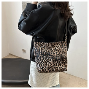 Detail of leopard print canvas bucket bag with black leather strap on model