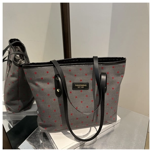 Detail view of large grey tote bag with red polka dots and black shoulder straps