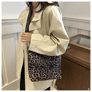 Detail of leopard print tote bag with black wide strap worn on a stylish trench coat