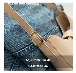 Close-up of golden metal adjustment buckle on beige leather shoulder bag strap