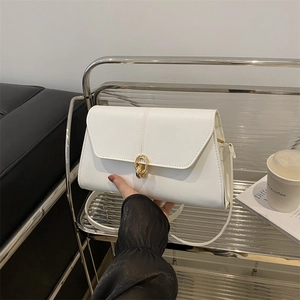 Elegant white PU leather crossbody bag with a golden double ring lock in a cafe setting