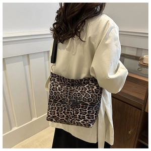 Detail of leopard print canvas bag with black wide strap and golden metal hooks