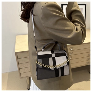 Detailed view of the black and white grid crossbody bag with gold chain on model