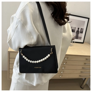 Detail of black faux leather shoulder bag with pearl chain and gold fashion logo