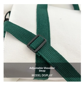Détail de la bandoulière réglable vert foncé avec boucle noire mate sur un sac en toile