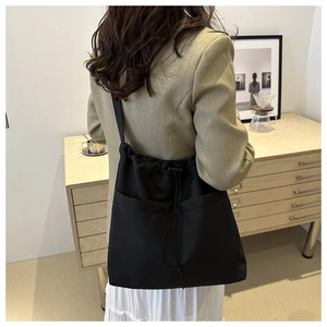 Detail of black waterproof nylon tote bag with drawstring closure and large front pockets