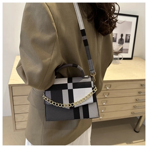 Détail du sac bandoulière à carreaux avec chaîne dorée et rabat sur un mannequin