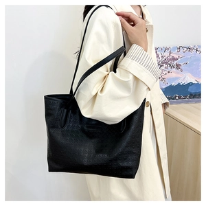 Detail of black tote bag with houndstooth embossing shown in a cozy interior setting