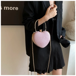 Detailed view of pink heart-shaped glitter bag with gold metal handle and chain strap