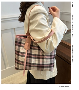 Side view of a large plaid tote bag with pink leather straps worn by a model