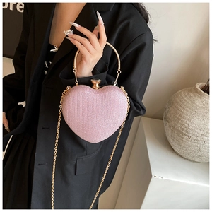 Macro shot of pale pink heart clutch bag with gold handle and delicate chain strap