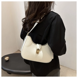 Detailed view of cream crescent bag with gold twist lock worn by model on black outfit