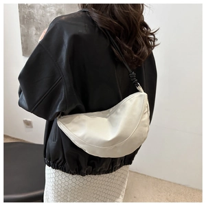 Detail of white half-moon crossbody bag featuring a unique knotted shoulder strap design