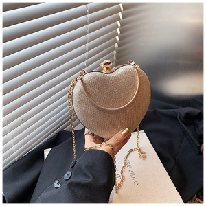 Close-up of heart-shaped clutch bag with champagne gold glitter and chain strap