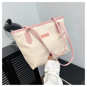 Detail of white leather tote with pink trim, embossed patterns and brand logo label