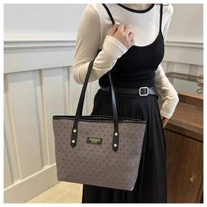 Détail du cabas gris à imprimé cœurs avec étiquette en cuir noir et rivets métalliques